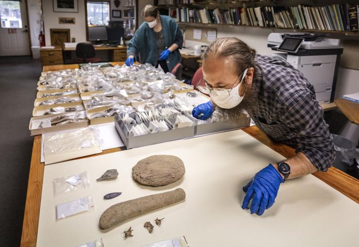 Carl Sholin, archaeologist for the North Cascades National Park Service Complex, leans in close to inspect precontact artifacts dug up near Ross Lake, on March 16, 2022. Those closest to the camera are mammal remains, fish club, culturally modified ston...