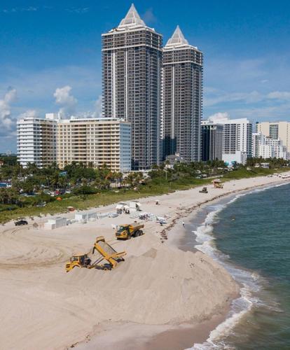 Trucks offload sand near an eroded stretch of shoreline near Indian Beach Park on Wednesday, Oct. 12, 2022, in Miami Beach, Florida.
