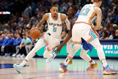 The San Antonio Spurs' Dejounte Murray drives around a pick set by Zach Collins against the Dallas Mavericks at American Airlines Center on April 10, 2022, in Dallas.