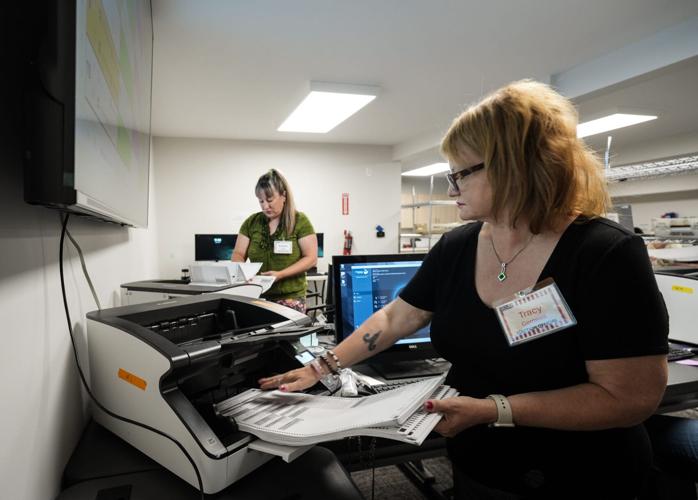 Election officials Tracy Cornwell, right, and Kristen Cole feed mail-in ballots through a tabulator, Thursday, July 30, 2026, at