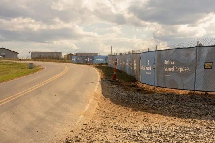 Signage along a chain-link fence announces the future AdventHealth Hospital in Weaverville, under construction on the other side of the fence on Sept. 11, 2026.