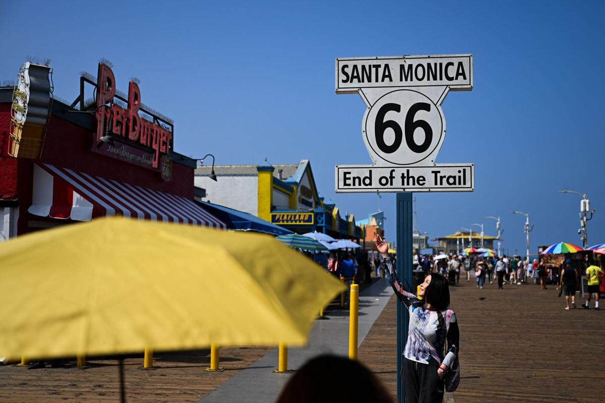 People take pictures with a sign at the end of Historic US Route 66 at the Santa Monica Pier on the Pacific Ocean in Santa Monica, California on July 28, 2026.