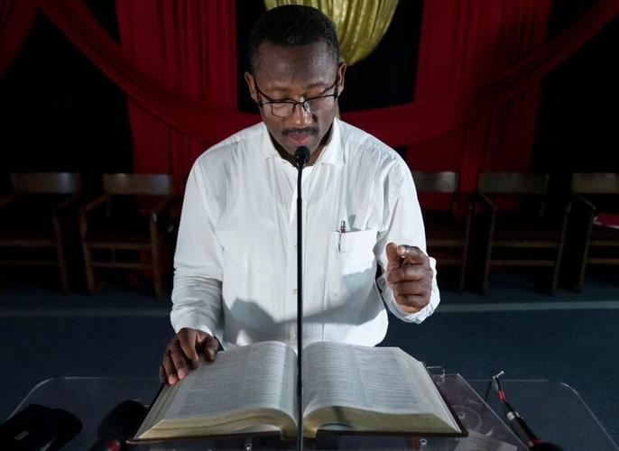 Seventh Day Adventist pastor Michelet William stands at a pulpit as he reads out Jeremiah 7:1-7 in French for a photo Monday, July 13, 2026, at the church he leads on the west side of Indianapolis. William’s congregation includes Haitian worshippers, ma...