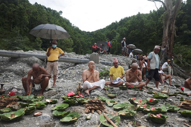 Men perform last rites for missing family members after being unable to recover their bodies following flash floods and mudslides, in Trishuli