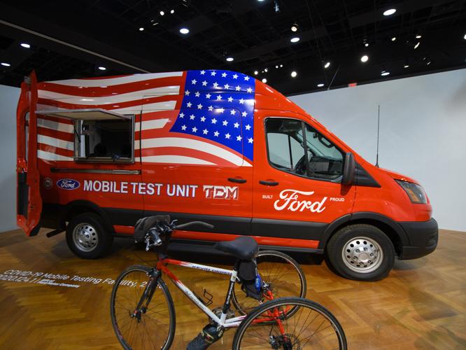 A Ford Transit van converted for use as a Mobile Test Unit is on display with a custom tricycle on display at a new exhibit at the Henry Ford Museum.