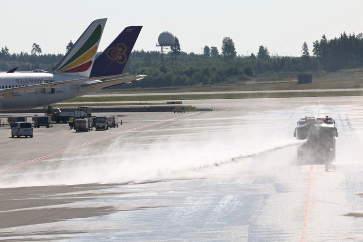 A vehicle from Oslo Airport’s fire rescue services sprays water onto the runway at the airport, to combat heat, in Oslo
