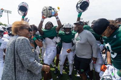 Chicago State University president Zaldwaynaka "Z" Scott, left, is greeted by the school's new Division I football team at a practice on Aug. 5, 2026, at CSU.