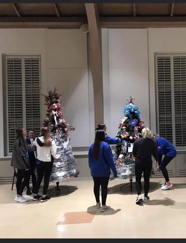 LU softball players wrapping Hospice trees with plastic film to aid in transport and delivery