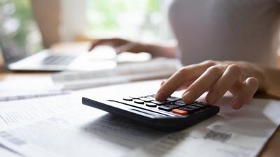 Young female hand counting on electronic calculator planning family budget