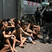 Police officers guard alleged criminals arrested in a crackdown in a Rio de Janeiro slum – IslanderNews.com
