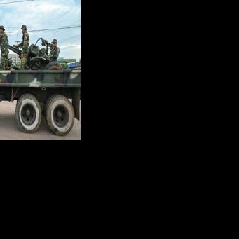 Cambodian soldiers stand on a military truck with an anti-aircraft gun in Oddar Meanchey province