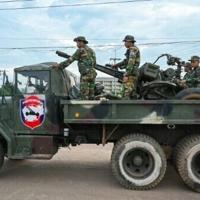 Cambodian soldiers stand on a military truck with an anti-aircraft gun in Oddar Meanchey province