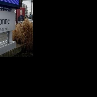 An election campaign sign showing Prime Minister Mark Carney is displayed along a street in Terrebonne, Canada