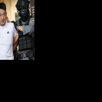 Chinese businessman She Zhijiang is escorted by Royal Thai Police out of the Suvarnabhumi Airport Police Station in Bangkok on November 12, 2025, before being extradited to China