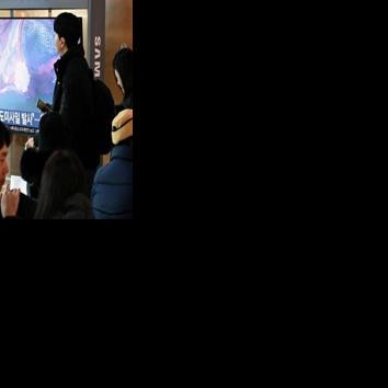 People in front of a TV screen showing footage of a North Korean missile test, at a train station in Seoul