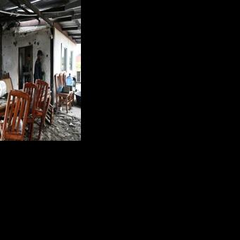 A security guard inspects an evacuated house that was hit by Cambodian artillery in Thailand's Surin province