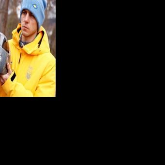 Ukrainian skeleton racer Vladyslav Heraskevych holds his helmet, which depicts victims of his country's war with Russia