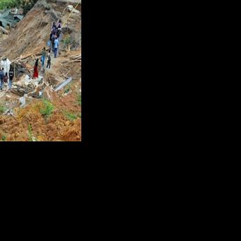 People walk past damaged houses following a landslide in Ulapane village in Kandy, Sri Lanka