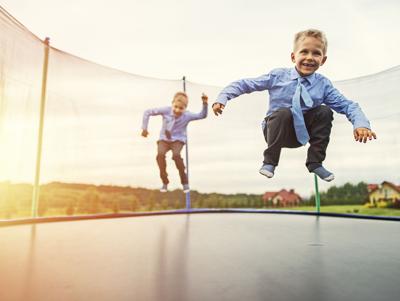 Little brothers wearing suits jumping on trampoline