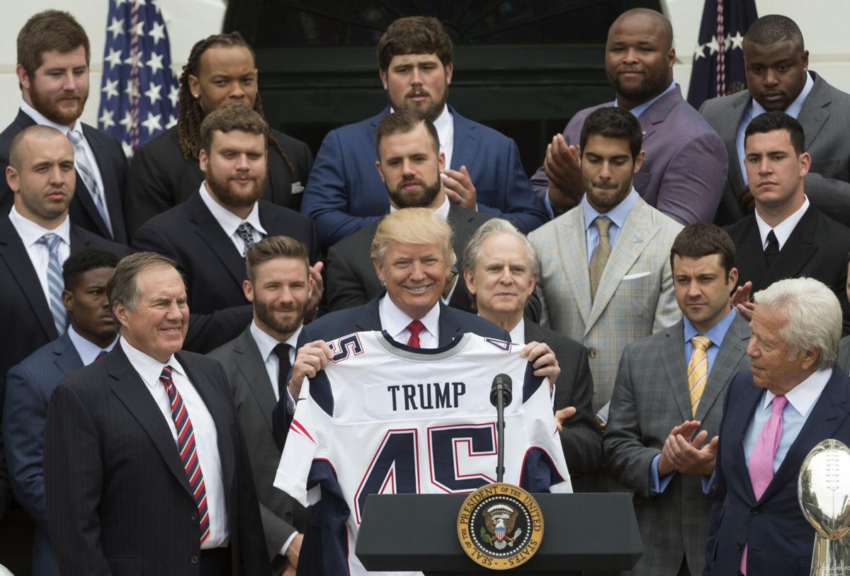 President Donald Trump holds a New England Patriots Super Bowl jersey next to coach Bill Belichick, left, and owner Robert Kraft, right, as he welcomes the Super Bowl champion Patriots to the White House on the South Lawn on April 19, 2017 in Washington, D.C..