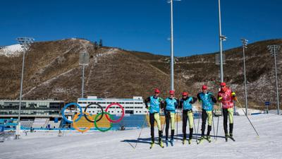 German cross-country skiers and coaches look on during training.