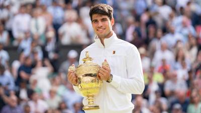 carlos alcaraz holds his trophy at wimbledon