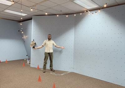 Andy Eisenburg stands in front of a climbing wall in KAP's youth space