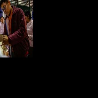 Military chief Min Aung Hlaing (back C) watches a voter ink their finger as he visits a polling station during the final phase of Myanmar's general election in January