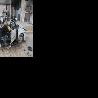 Palestinian children look at a destroyed vehicle in Gaza City