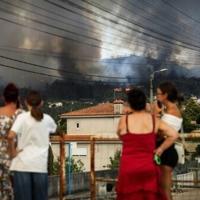 Residents watch as a wildfire burns in the surrounding hills in Gondomar, northern Portugal, on July 29, 2025