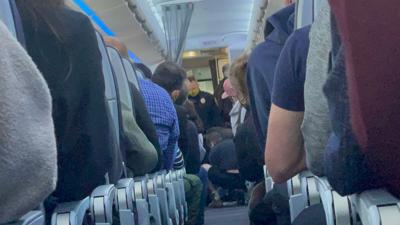 An American Airlines flight attendant hit an 'unruly passenger' in the head with a coffee pot as he tried to open the plane's exit door
