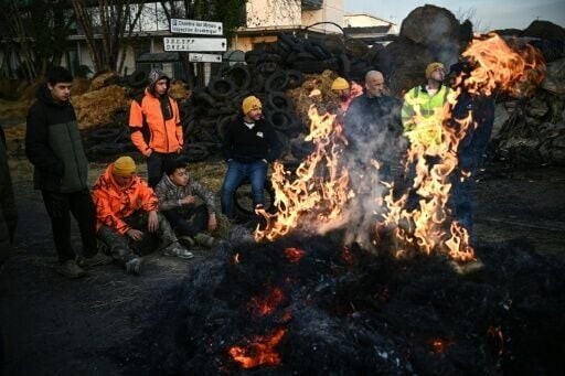 Farmers of the CR47 union stand by a bonfire during a proteset in southwestern France