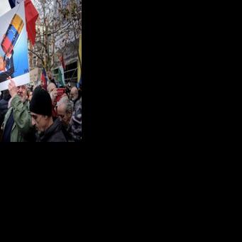 A protester holds a caricature of Donald Trump drinking from a Venezuelan oil barrel