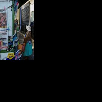 A woman in La Paz stands next to a kiosk displaying newspapers with front-page coverage of Bolivia's presidential election