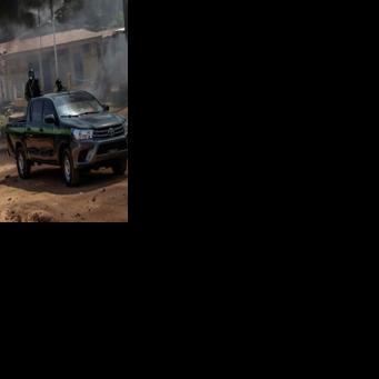 Guinea Bissau security forces patrol cars drive near burning tyres