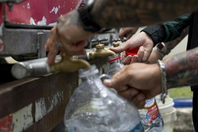 Residents collect water from a tanker truck amid government-imposed water rationing in San Juan, Puerto Rico, in August 2026.