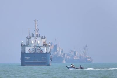 A small motorboat passes anchored vessels in the Strait of Hormuz off Bandar Abbas, Iran, on June 11, 2026.
