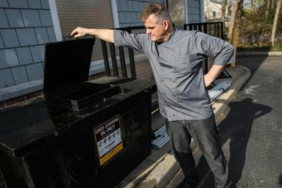 A restaurant owner looks at a tank for collecting used cooking oil.