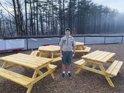 Declan Ulricson proudly stands with the picnic tables
