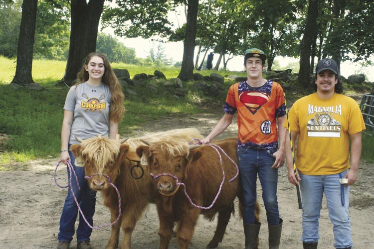 Students Maggie, John, and Jack stand with Bear