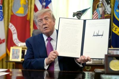 President Donald Trump holds up a signed executive order in the Oval Office in August 2026.