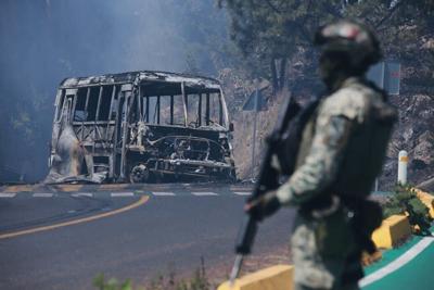 A soldier stands guard by a charred vehicle in Michoacán state, Mexico, on Feb. 22, 2026.