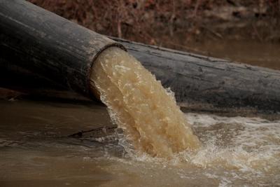 A pipe carries water and raw sewage into the C&O Canal, parallel to the Potomac River.