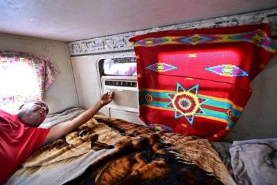 Elbert Yazzie adjusts his air conditioning unit in Tuba City, Ariz., in 2025.