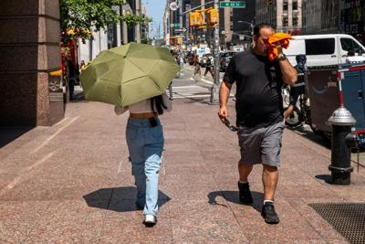 People try to stay cool on the sweltering streets of Manhattan during a heat wave in July 2025.