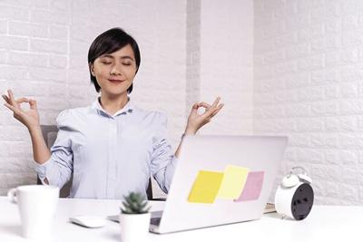 Woman meditating holding her hands in yoga gesture at office