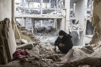 A woman sifts through the rubble in her home after it was damaged by a missile on March 15, 2026, in Tehran.
