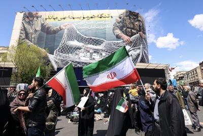 Iranians hold national flags in Tehran's Revolution Square on April 8, 2026, after the United States and Iran agreed to a two-week ceasefire.