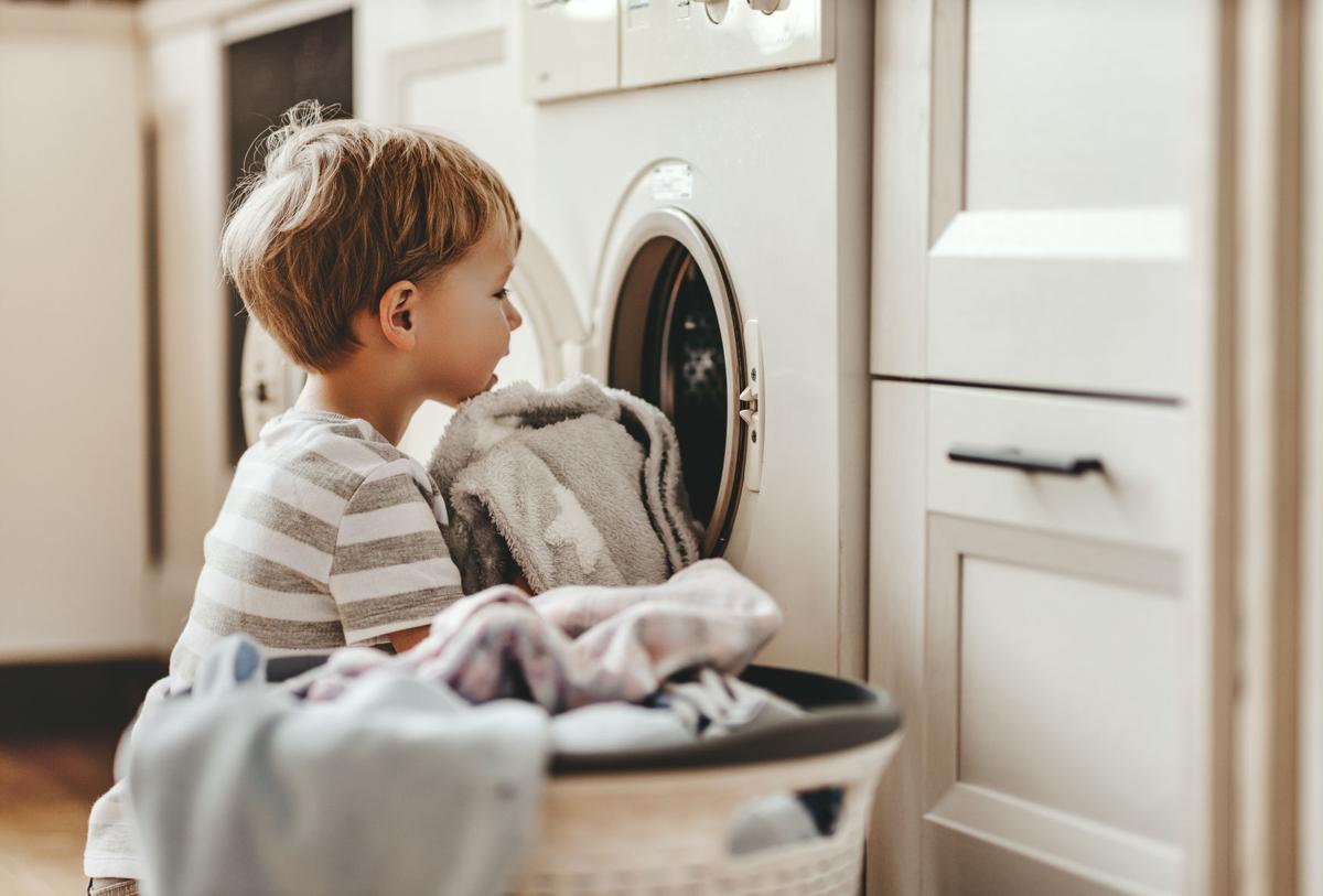 happy householder child boy in laundry with washing machine