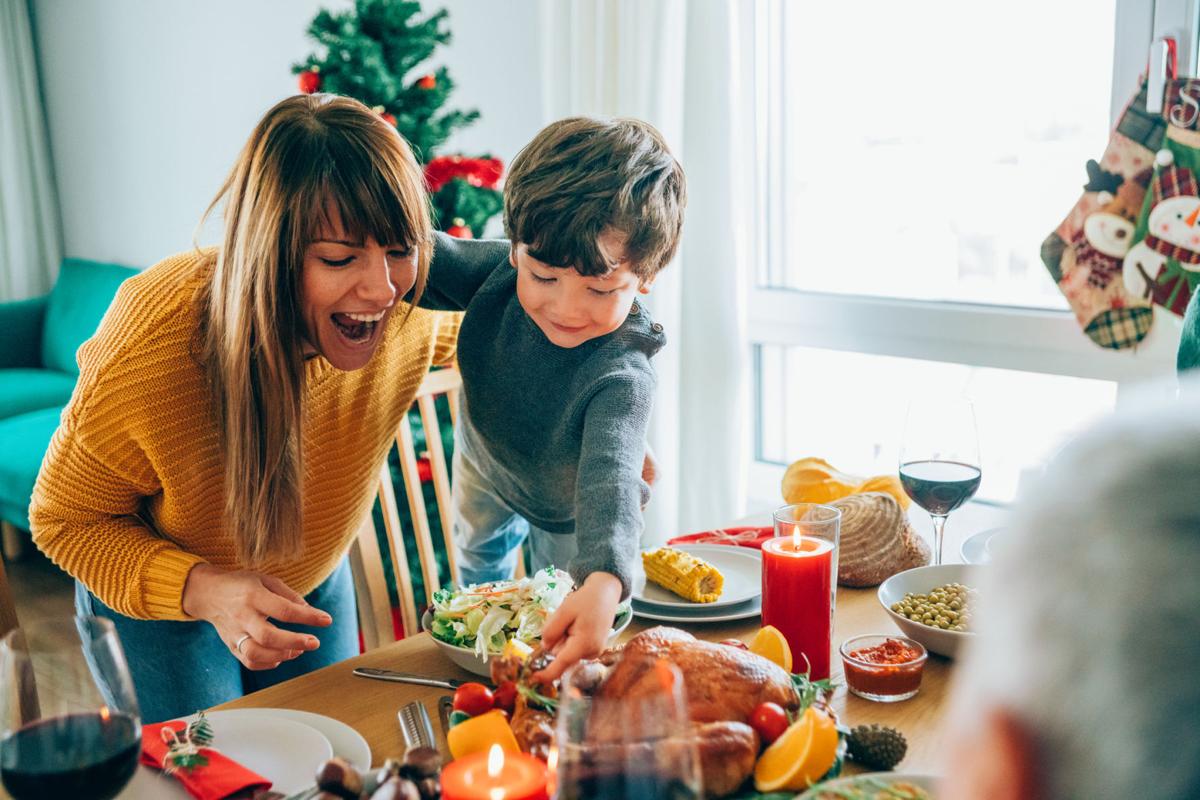 Happy mother and her son having fun while holding roasted turkey leg